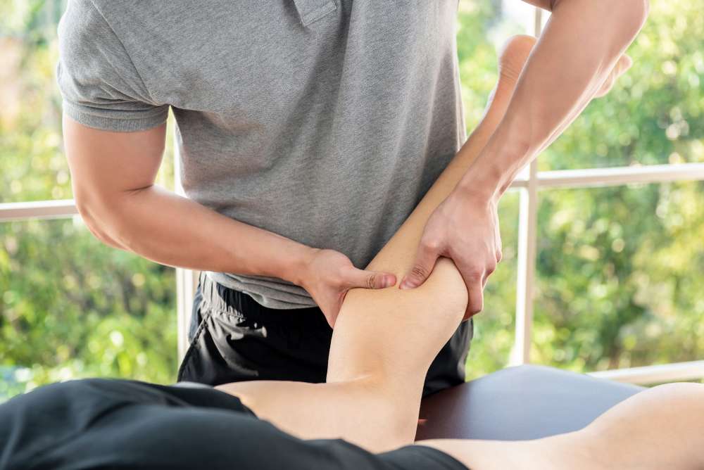 Physiotherapist reassuring a seated patient about calf injury recovery